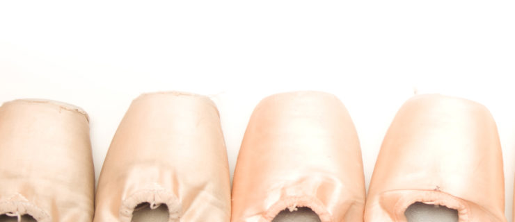 A photo of ballet slippers lined up on a white background.