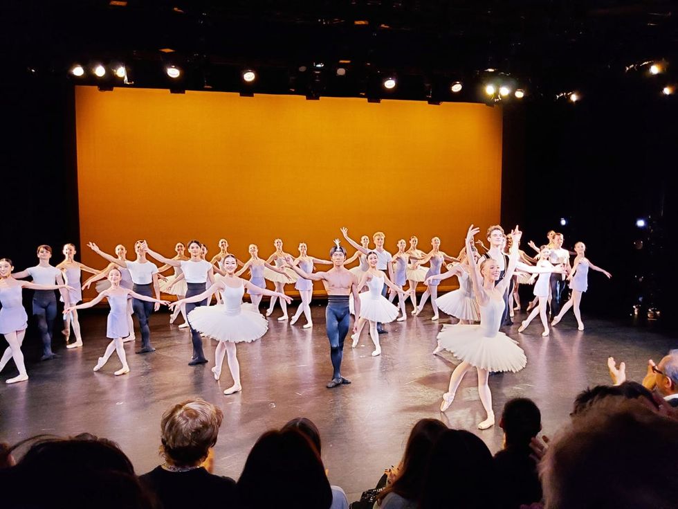 A curtain call for a performance, of dozens of students in various costumes.