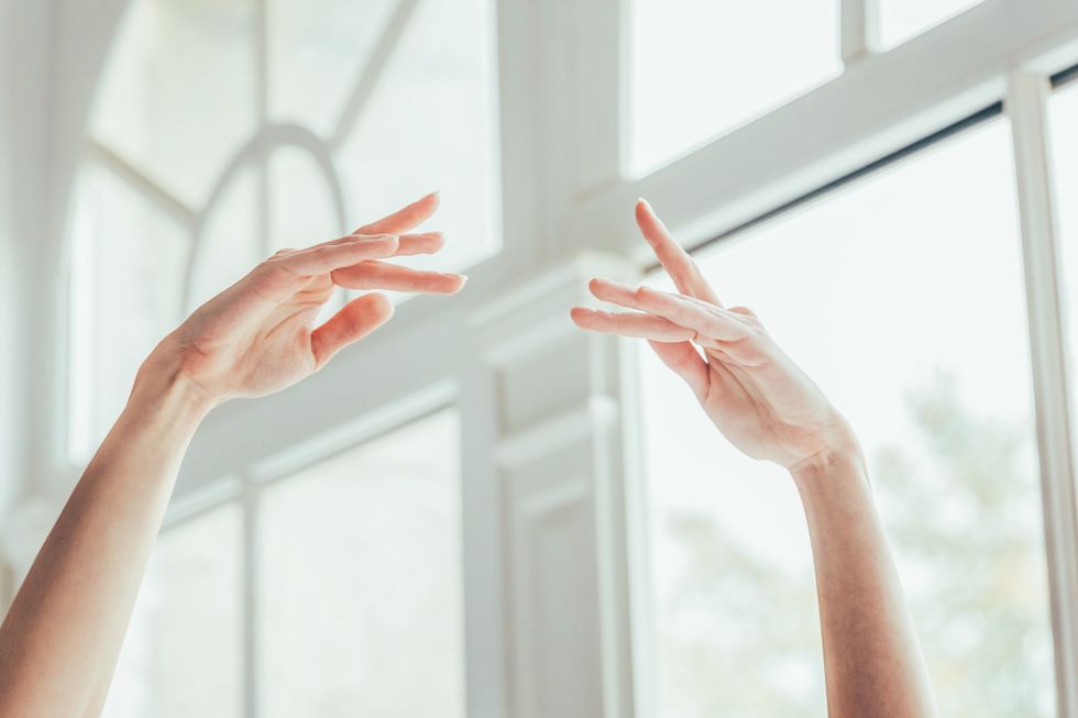 A pair of graceful female hands in fifth position photographed from the mid-arm up.