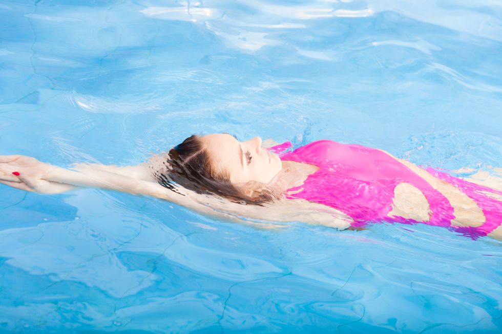 Woman in a pink bathing suit swimming in a pool