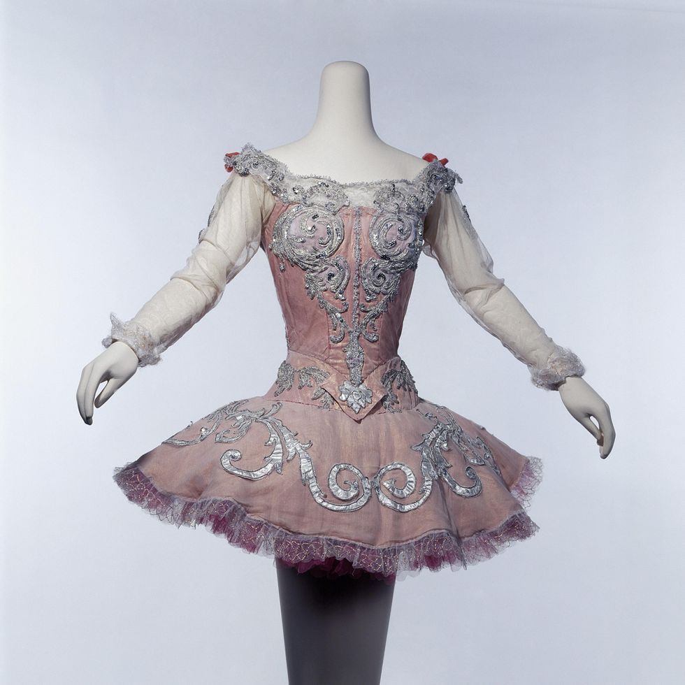 A white, headless mannaquin displays a short, pink tutu with filmy white chiffon sleeves and silver embellishments along the neckline, bodice and skirt.