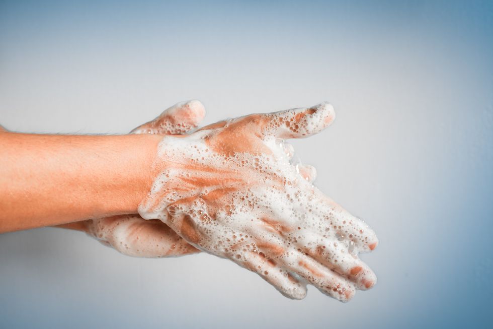 Soapy hands being washed against a blue background
