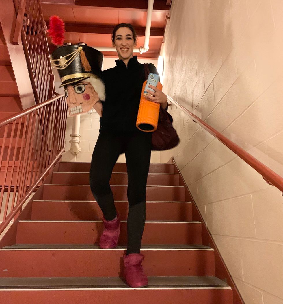 Dafoe walks down stairs, while wearing warm-up clothes and holding the Nutcracker head.