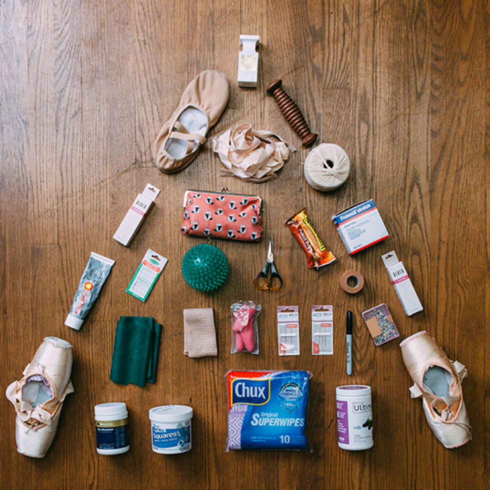 A triangle of dance bag items laid out on a wooden floor.