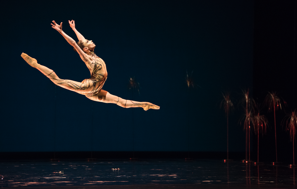 Andru00e9, in a gold bodysuit, leaps across the stage.