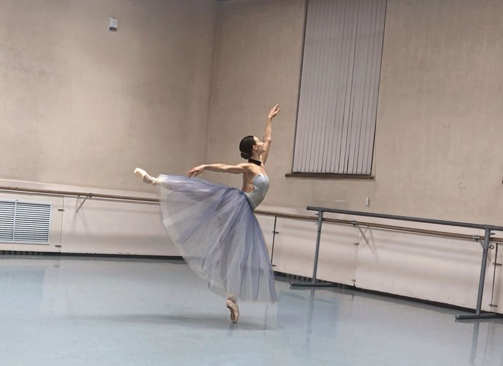 Shevchenko stands in arabesque in a studio wearing a long blue romantic tutu