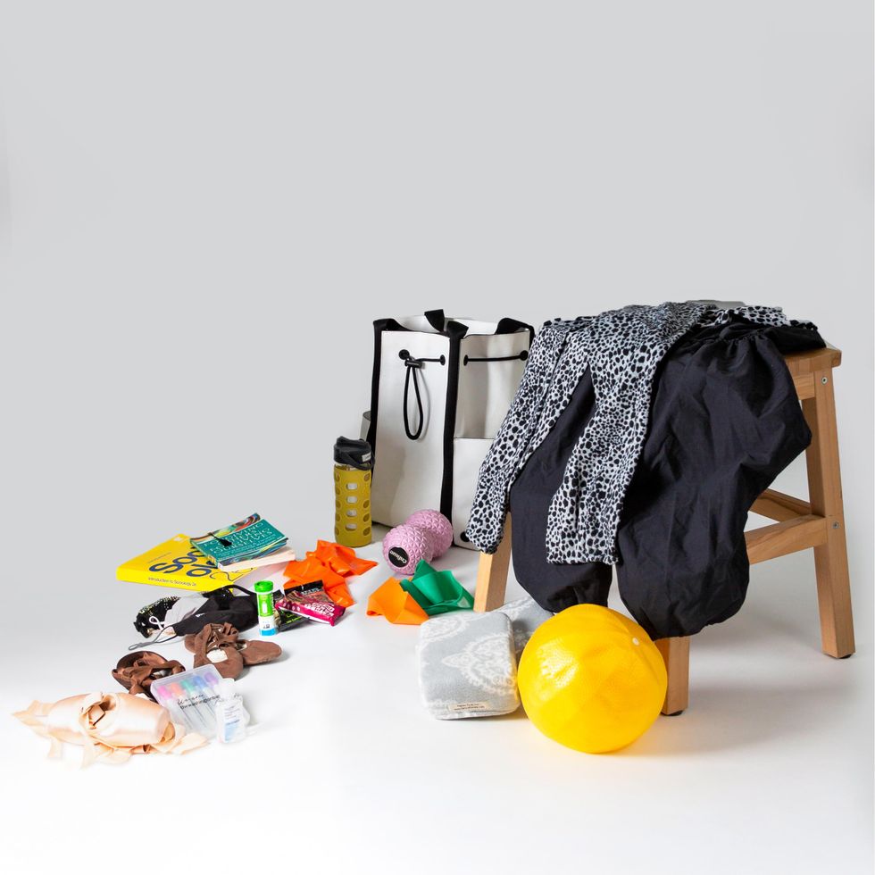 The contents of Ashley Murphy-Wilson's dance bag are laid out on a white floor. A few items are draped on a wooden stool.