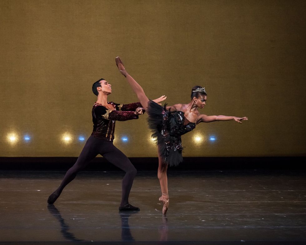 Wearing black tights and a burgundy velvet top, Francis Lawrence lunges in tendu derriu00e9re and holds Ashley Murphy's right hand as she relevu00e9s into first arabesque allongu00e9.