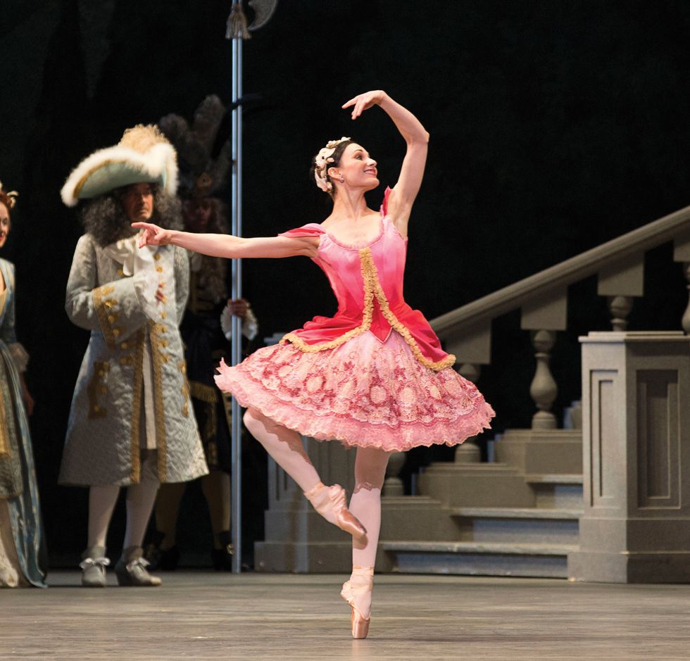 Sarah Lane in pink Aurora costume in a passu00e9 with one arm in the air onstage