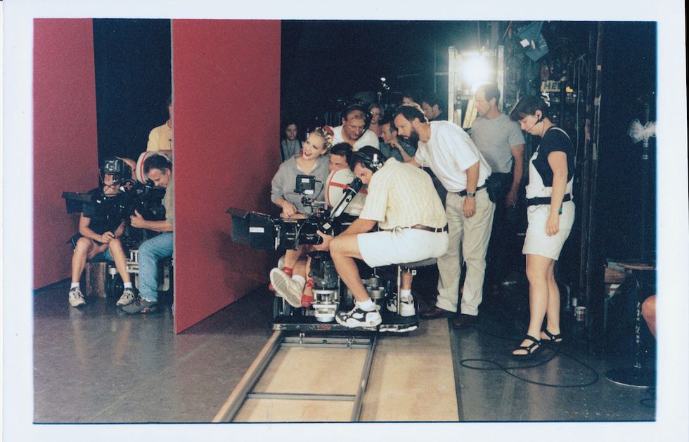 Schull behind the scenes on the film. She poses with members of the camera crew, sitting on one camera man's lap.