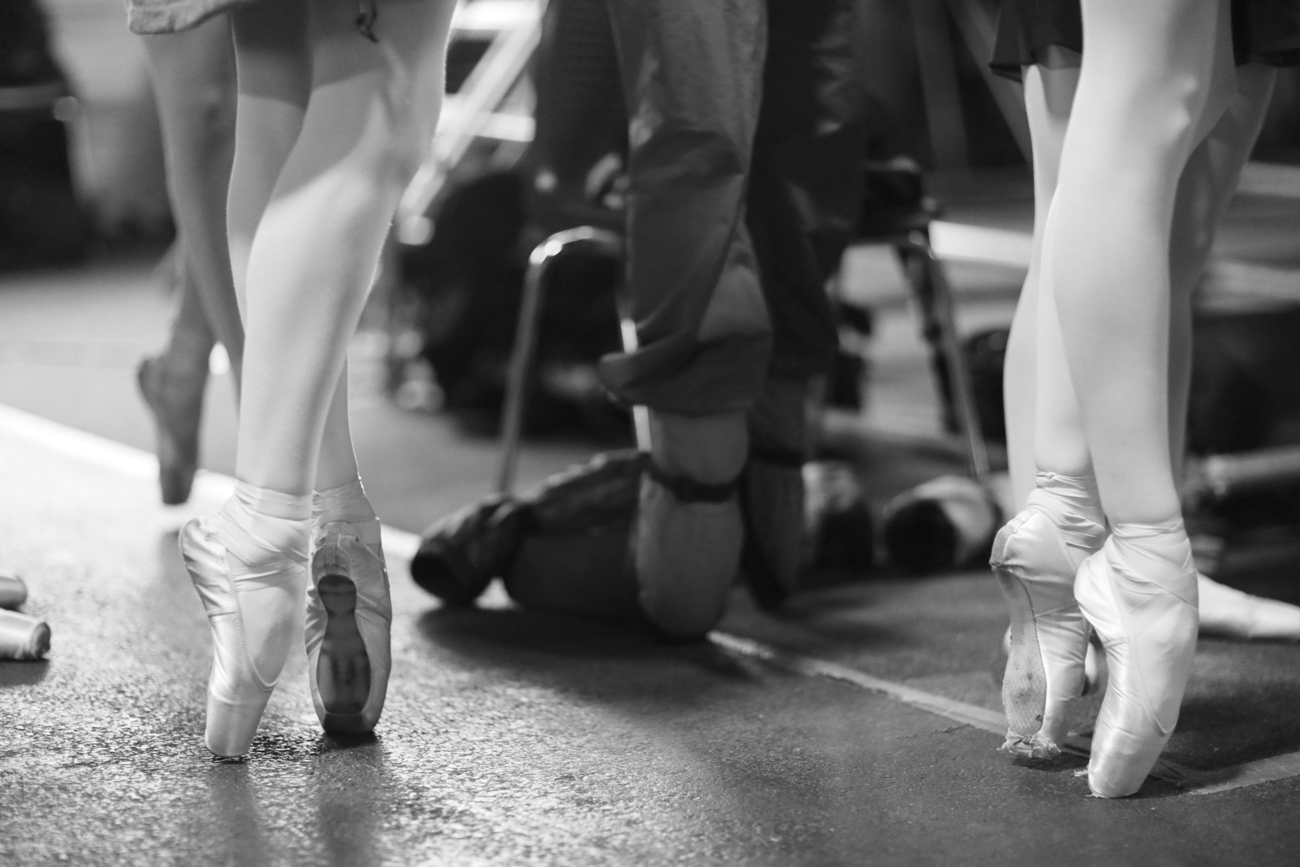 Black and white image of dancers' legs standing in fifth position en pointe
