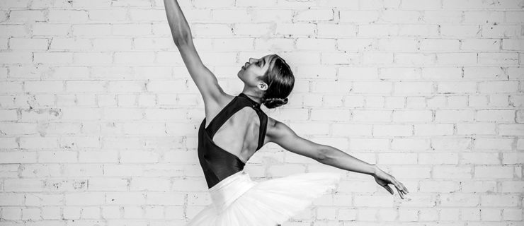 A black-and-white image of Ariel McCarty on pointe balancing in fourth position.of