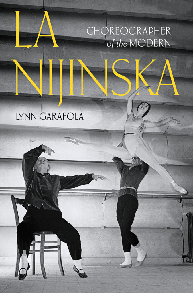 Photo shows the cover of the book "La Nijinska: Choreographer of the Modern" by Lynn Garafola. The book title is in large yellow lettering over a black and white photo showing NIjinska in a chair, working with a male and female dancer as they practice a lift.