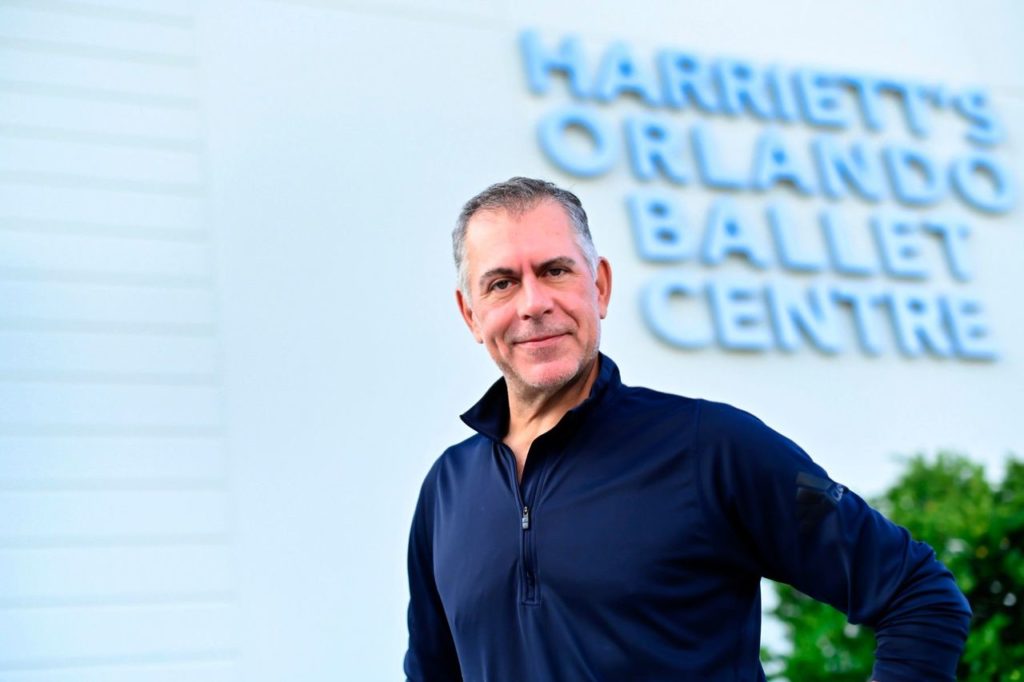 Jorden Morris stands outside Orlando Ballet's facilities, wearing a blue quarter zip sweater. 