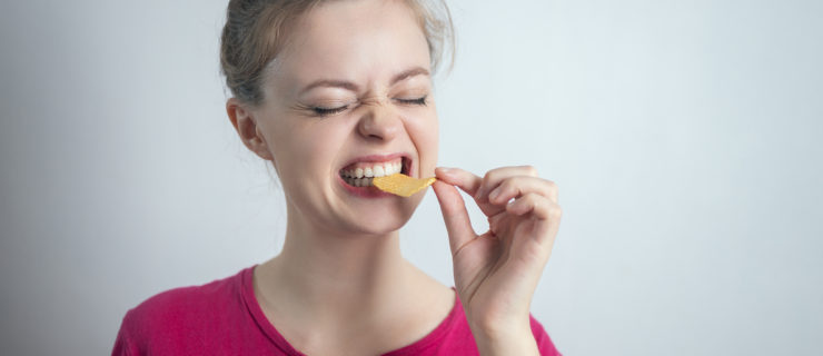 Smiling young Caucasian woman girl eating biting potato chips