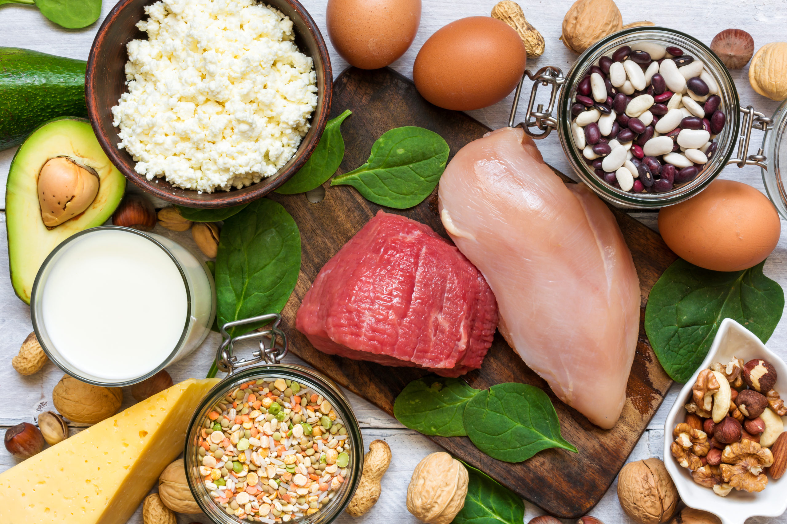 A spread of high-protein foods, including cheese, milk, chicken, lentils, nuts.