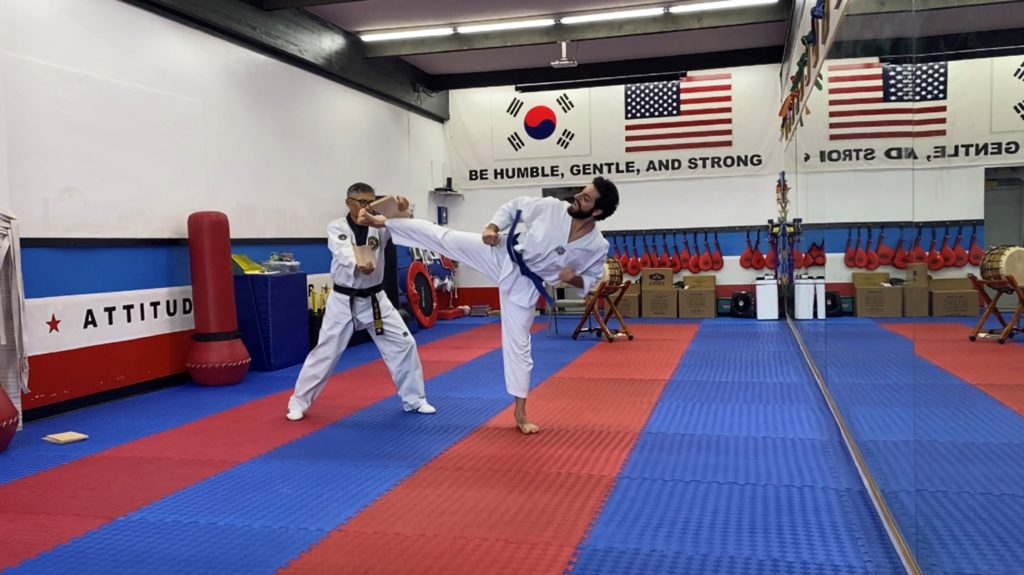 Tigran Sargsyan kicks sideways with his right leg to break a board held by a tae kwon do instructor.