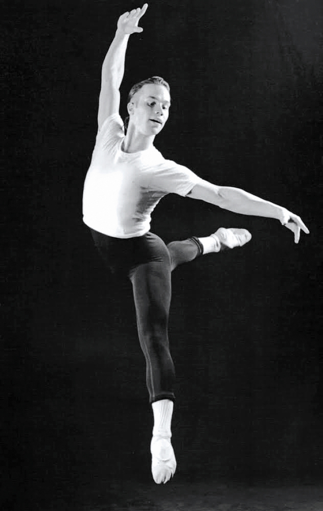 Abreu in a white dance t-shirt and dark-colored tights, leaping.