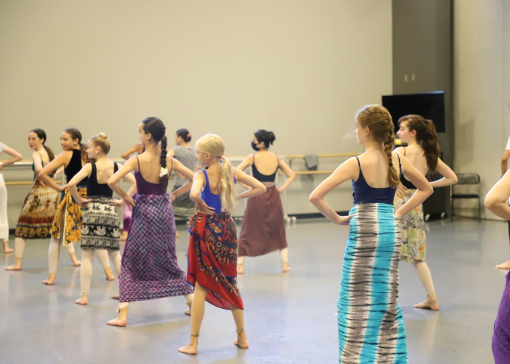 Young girls in an African dance class wearing colorful, printed cloth skirts.