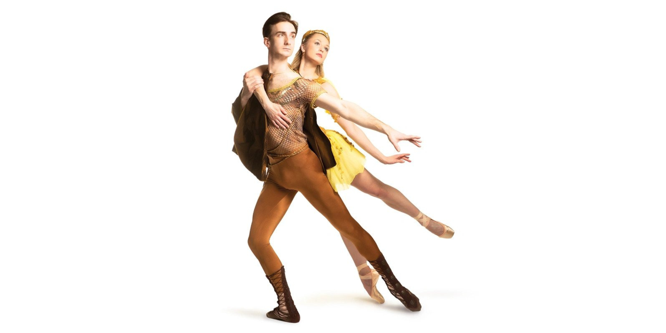In front of a blank white background, a pair of dancers performing as Orpheus and Eurydice pose doing a pas de deux together. The man, in rust-colored tights and brown Greek-esque costuming, lunges on his right leg in tendu derriere, his left arm extending back and his right arm wrapping behind to support his partner. The woman, in a yellow Greek-esque dress, wraps her right arm around his chest as she leans on his back in a low arabesque on pointe, extending her left arm to match his line. They both look into the distance.