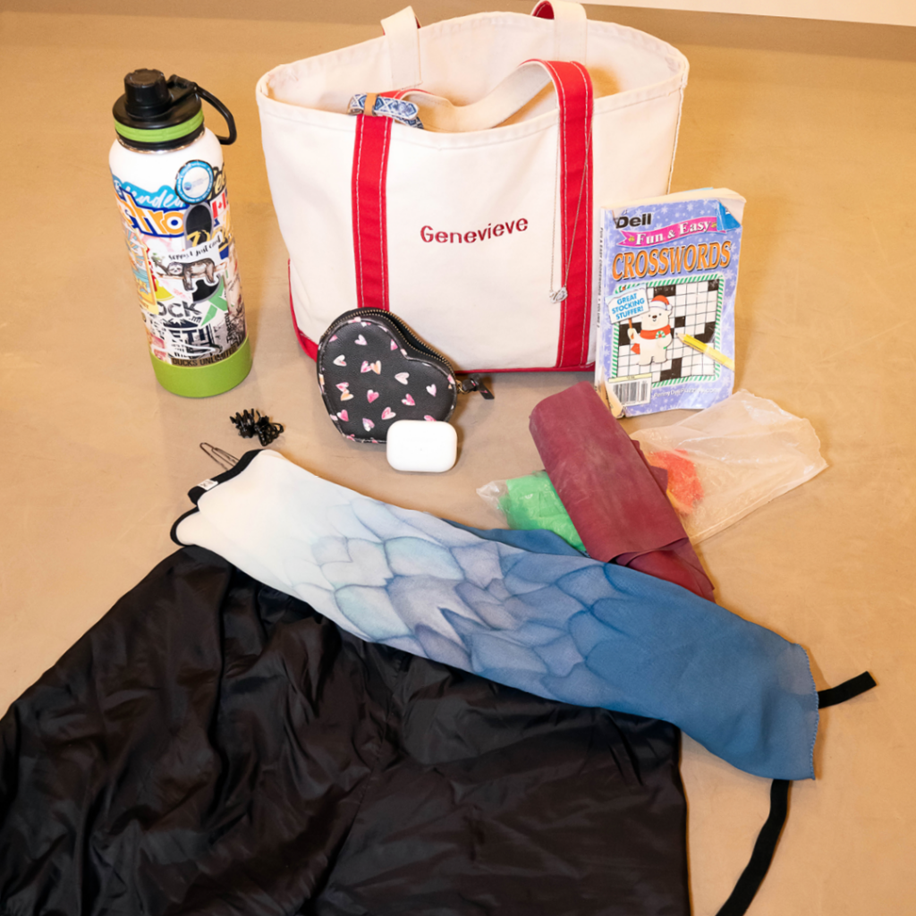 Genevieve Penn Nabity's dance bag, water bottle, skirt, trash-bag shorts, crossword puzzle book, TheraBand, hair accessories, AirPods, and snacks.