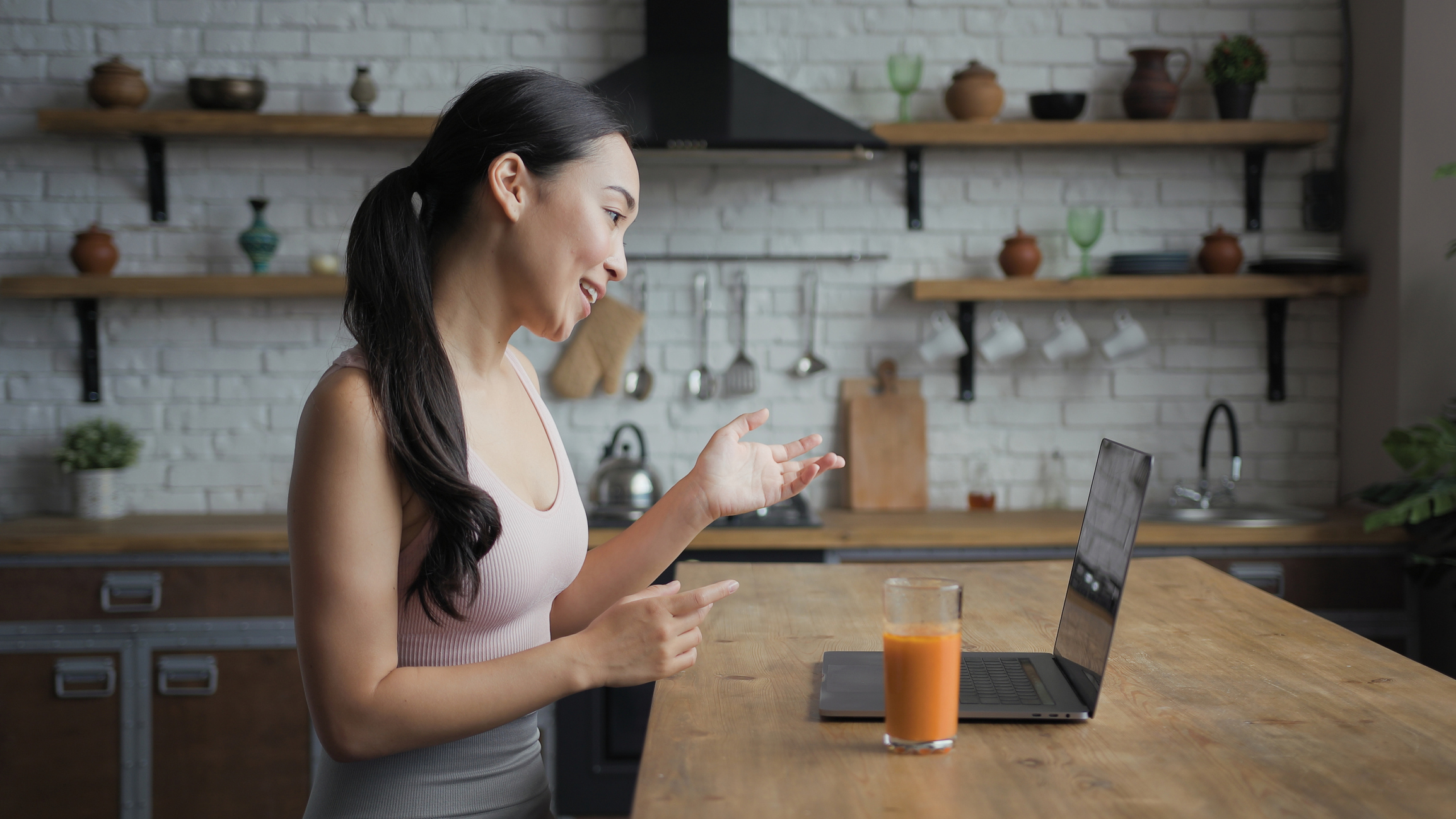 Asian woman talking on a video call on laptop, side view