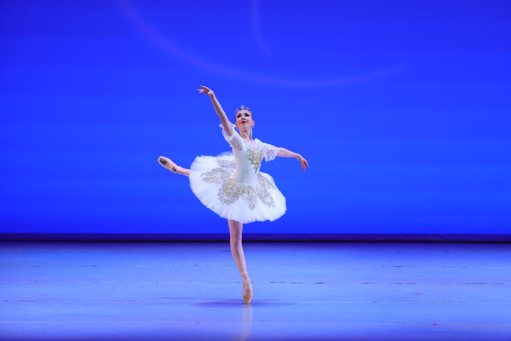 Onstage at YAGP, Julie Joyner performs the Aurora Act 2 variation in a sparkling white tutu. She does a piqué attitude on the croisé derriere line.