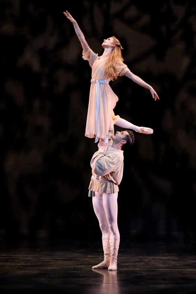 Danielle Brown and Ricardo Graziano in Frederick Ashton's <i>The Walk to the Paradise Garden</i>/ Graziano lifts Brown in a torch lift; they both wear soft pink costumes.