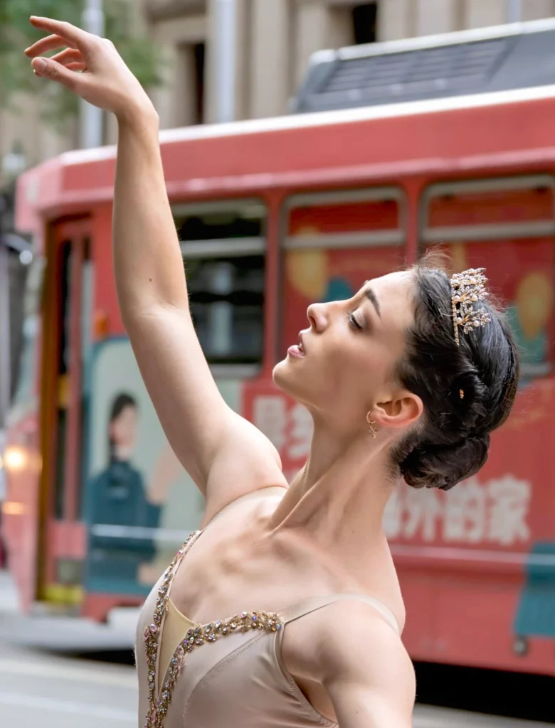 A close-up profile shot of Bianca Carnovale in a tiara, posing on the street in front of a red bus. She is looking toward her raised right arm.