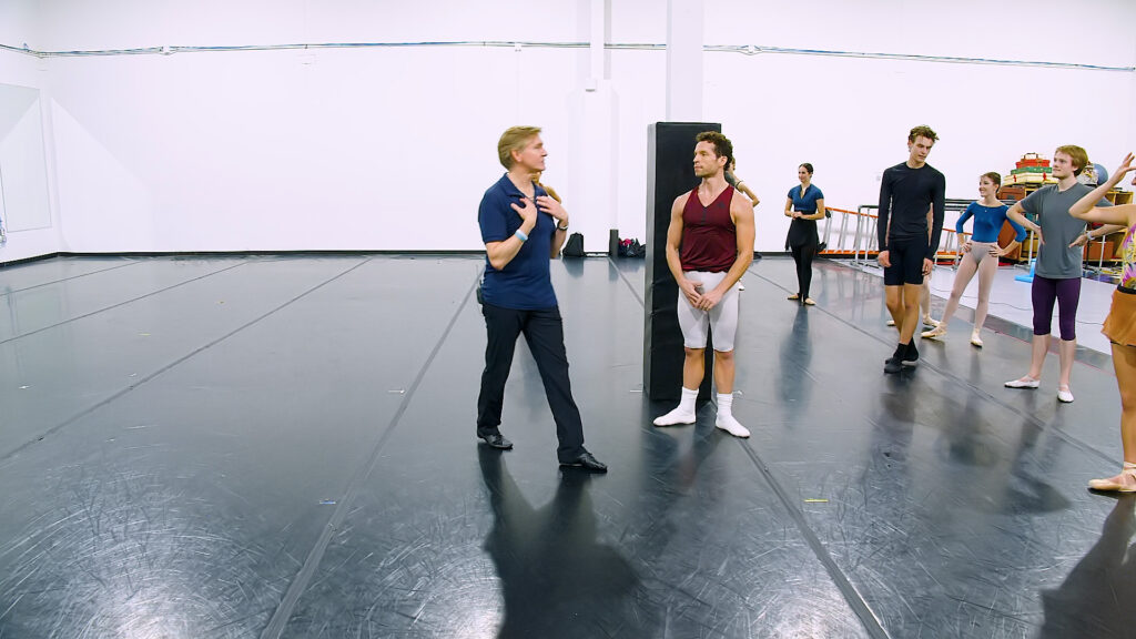 Tim O'Keefe leads a rehearsal with artists of Texas Ballet Theater. They stand in a large studio, and they listen as O'Keefe speaks.