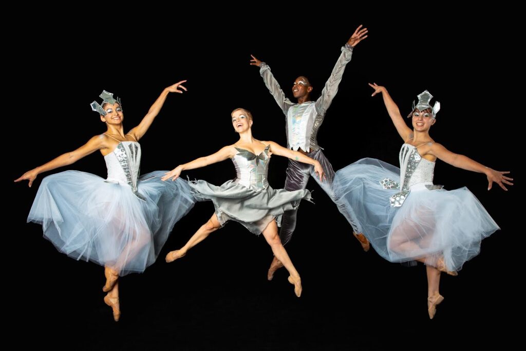 Post:Ballet dancers as the Nutcracker Bird Snowy Owl with Berkely Ballet Theater studio company members as snowflakes. The four dancers are suspended mid-air in various sauté poses in front of a black backdrop.