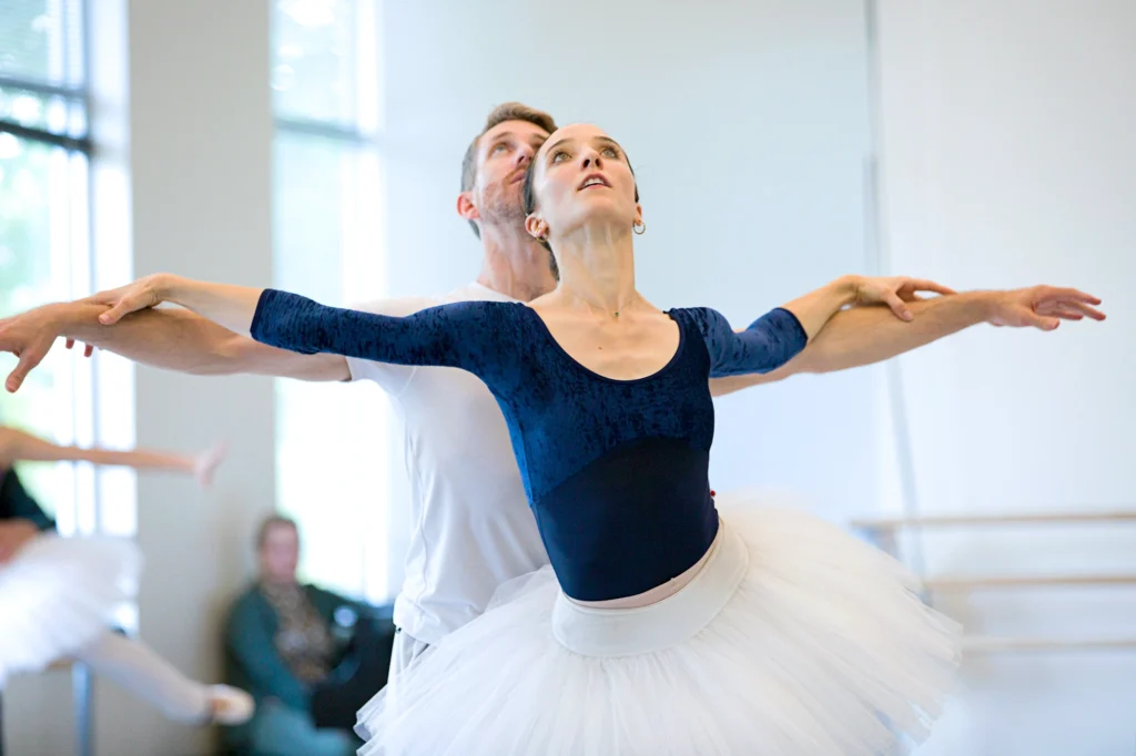 Carly Wheaton and Brian Simcoe in rehearsal for <i>Swan Lake</i>. Wheaton wears a long-sleeved navy leotard and white practice tutu.