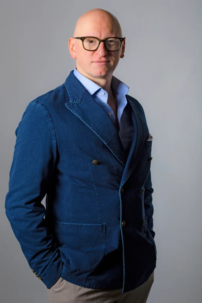 Francesco Ventriglia poses for a headshot with a content look on his face. He wears a dark blue suit jacket.
