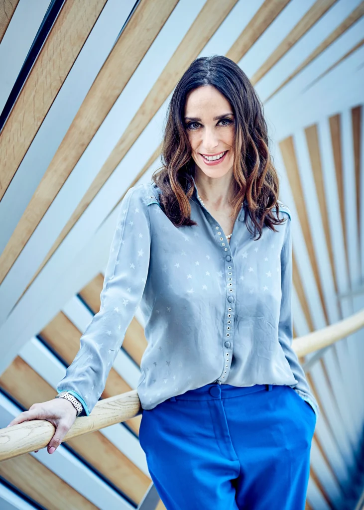 Viviana Durante poses for a portrait photo in a light blue button down, smiling at the camera.