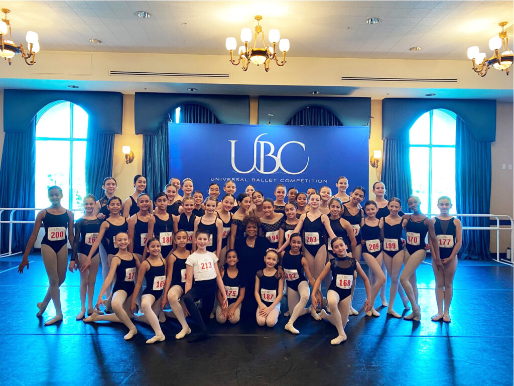 Charmaine Hunter, a judge for Universal Ballet Competition, poses with a large group of ballet students. They all smile for the camera.