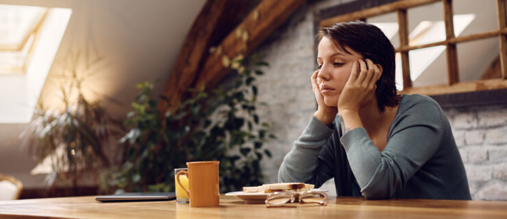 A young woman sitting at a dining table during breakfast does not have an appetite.