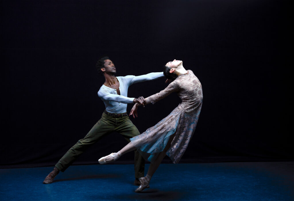 Hee Seo leans forward on pointe in a low arabesque, arching back, as Calvin Royal III holds onto her hands and counterbalances her in a deep lunge.