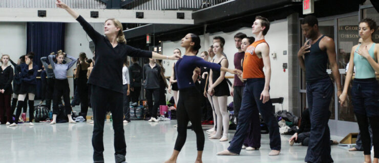 Stoner Winslett demonstrates an open allongé port de bras position in rehearsal with a large group of dancers.