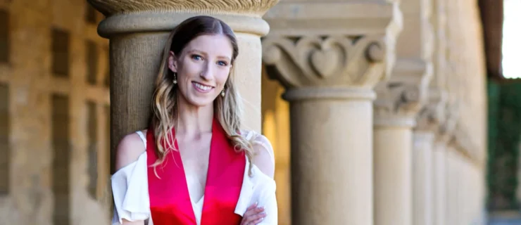 Ellie Prince poses at Stanford University, wearing a white dress and red stole.