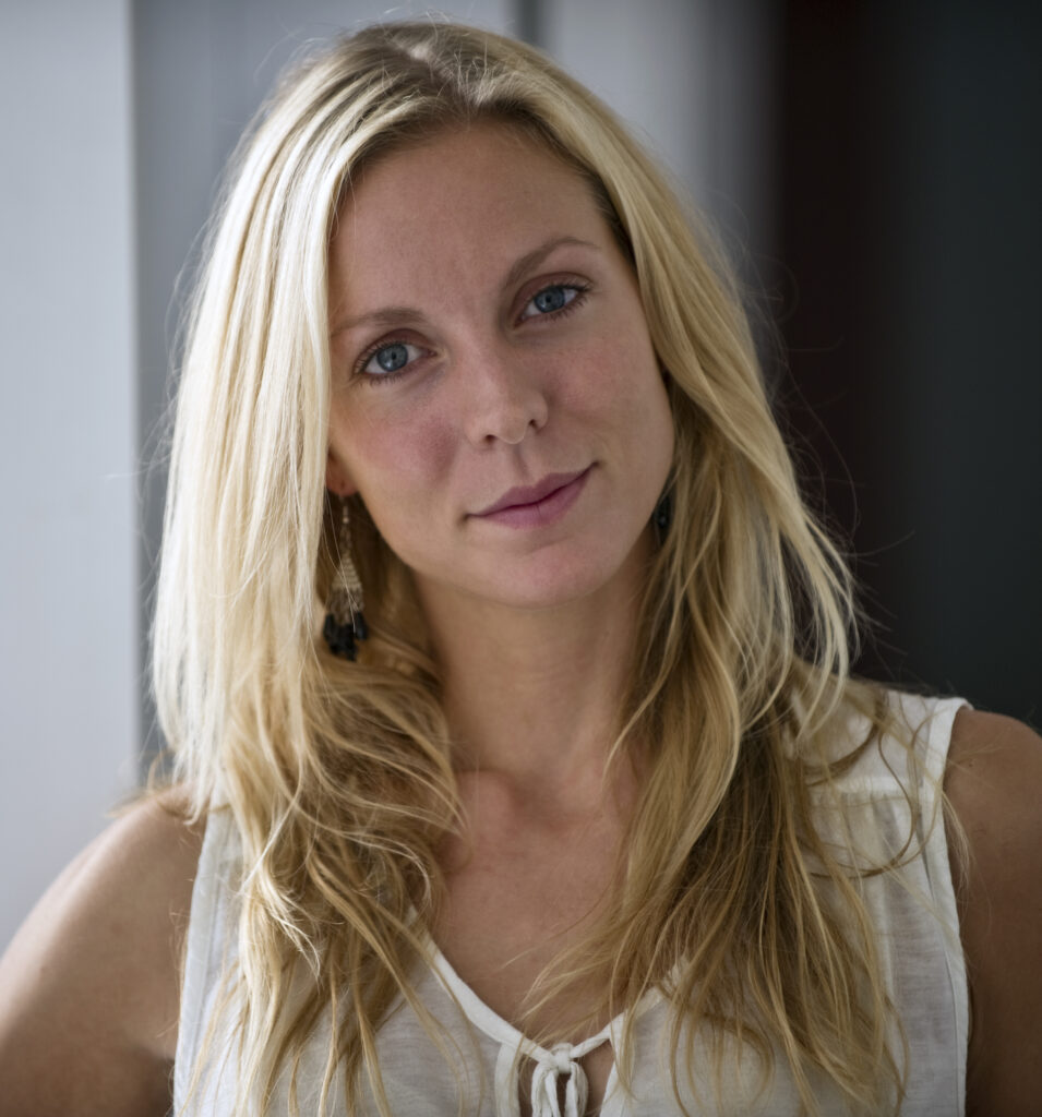 Cina Espejord, shown from the neck up, tilts her head slightly and smizes into the camera for a portrait. She wears a white formal tank top.