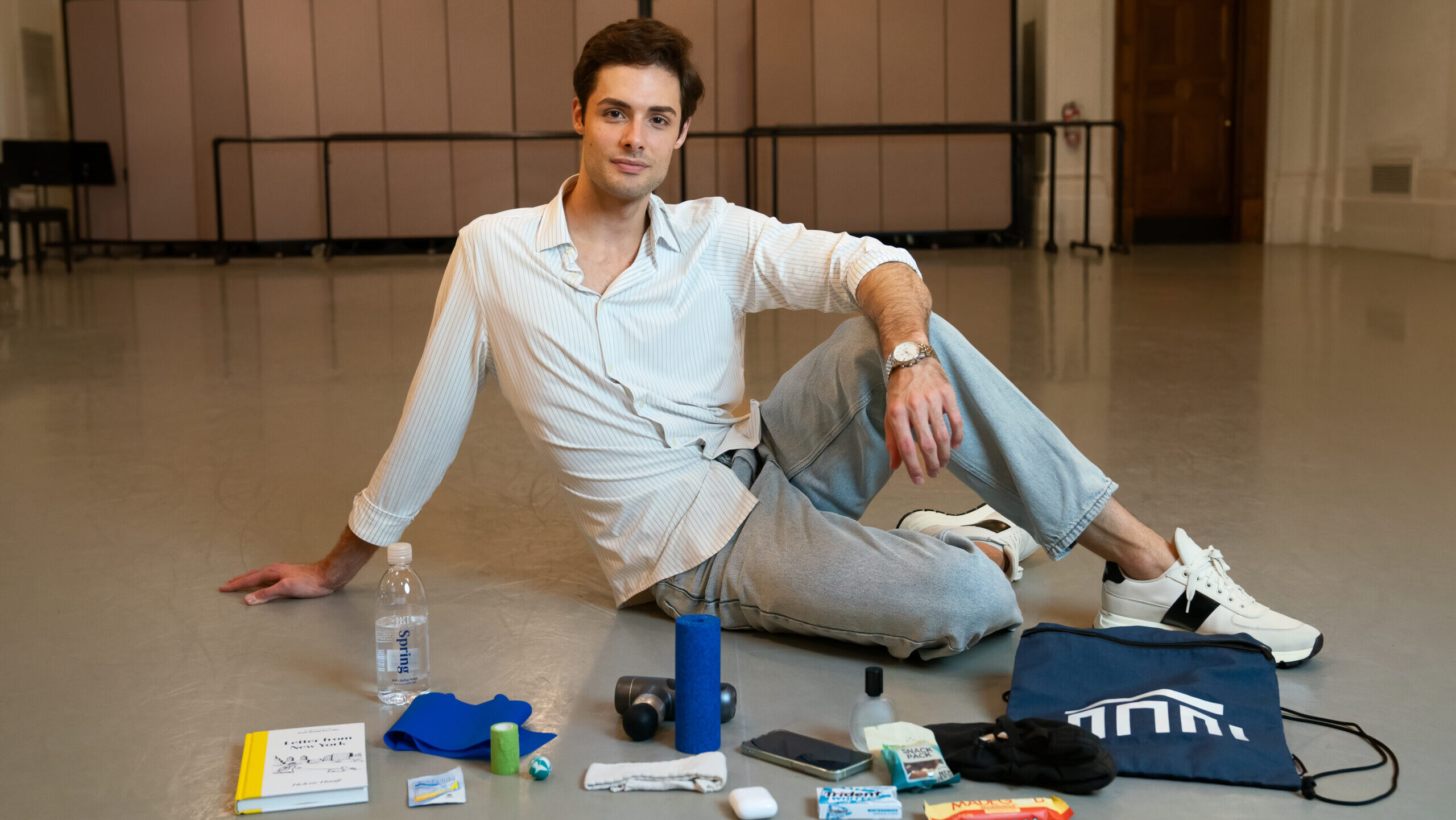 Jacopo Tissi lounges in a dance studio with the contents of his dance bag in front of him.