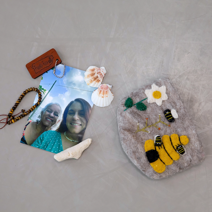 A felt beehive bag, a wooden beaded bracelet, some shells and coral, and a photograph of Rojas' mother and grandmother