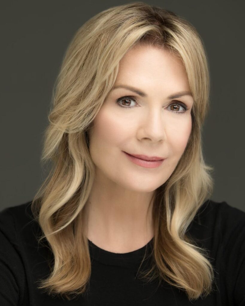 Diane di Stasio, shown from the shoulders up, wears a black long-sleeved shirt and turns her head slightly with a small smile for a headshot.