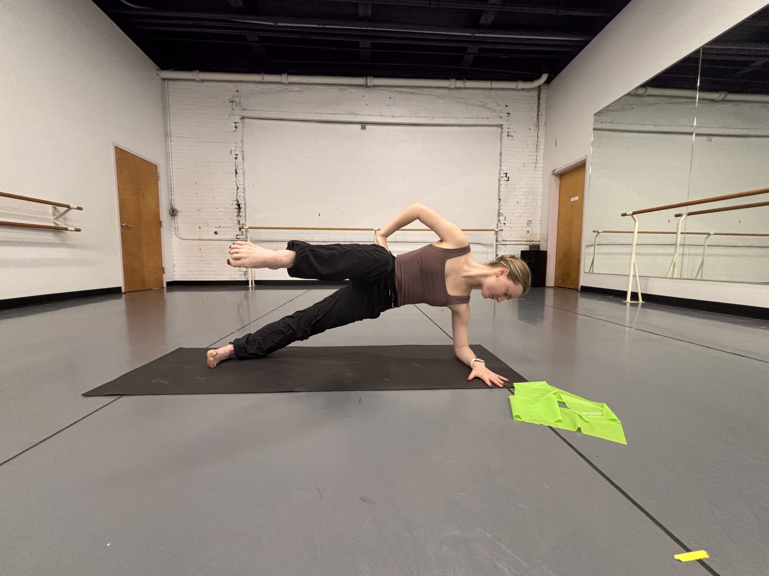 Lydia Marbach does a side plank with the top leg lifted forward, her knee at a 90 degree angle and her shin facing the camera.