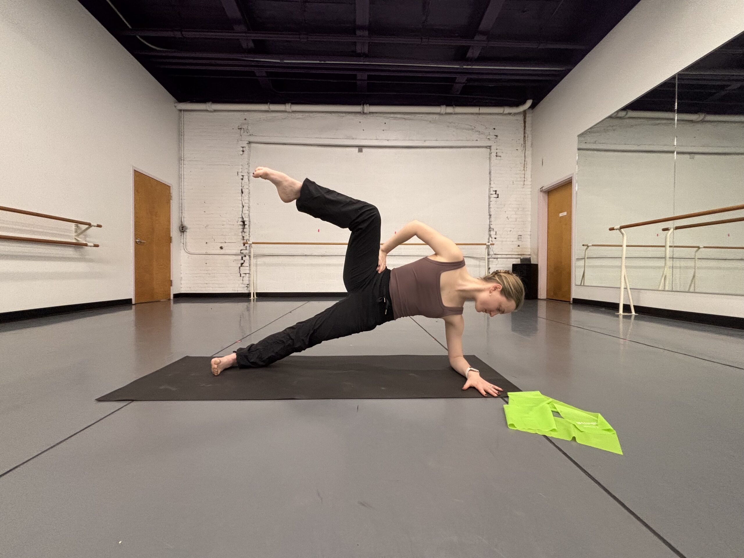 Lydia Marbach does a side plank with the top leg lifted up to the side, her knee at a 90 degree angle and her shin facing the ceiling.