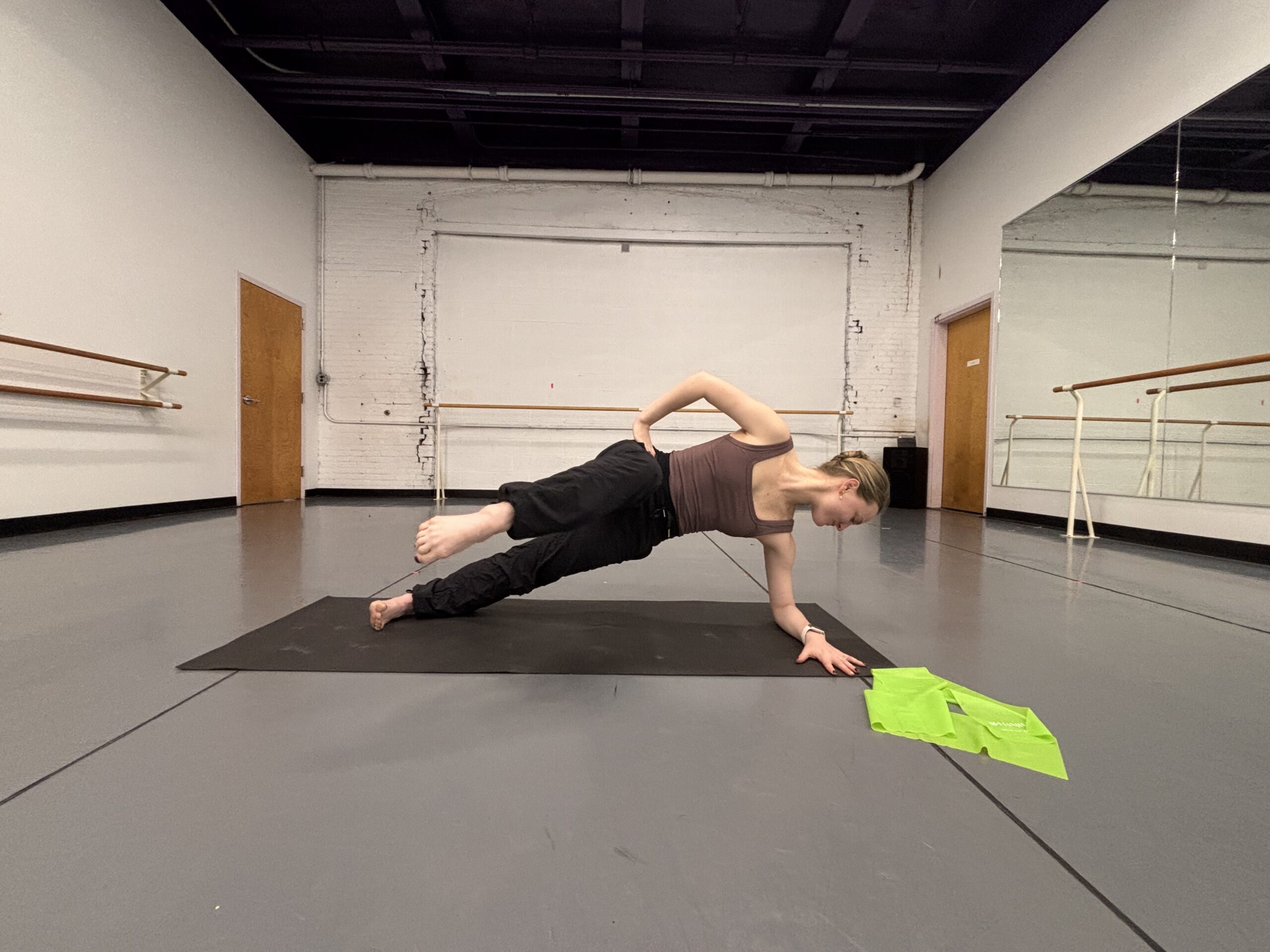 Lydia Marbach does a side plank with the top leg lifted forward, her knee at a 90 degree angle and her shin facing the camera.