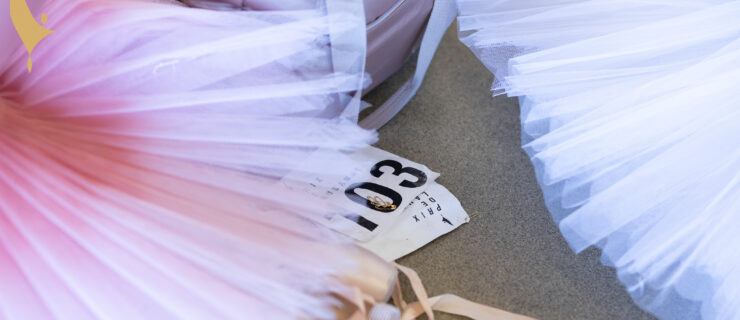 A close-up shot of two Prix competitors' practice tutus, with pointe shoes and audition numbers beneath.