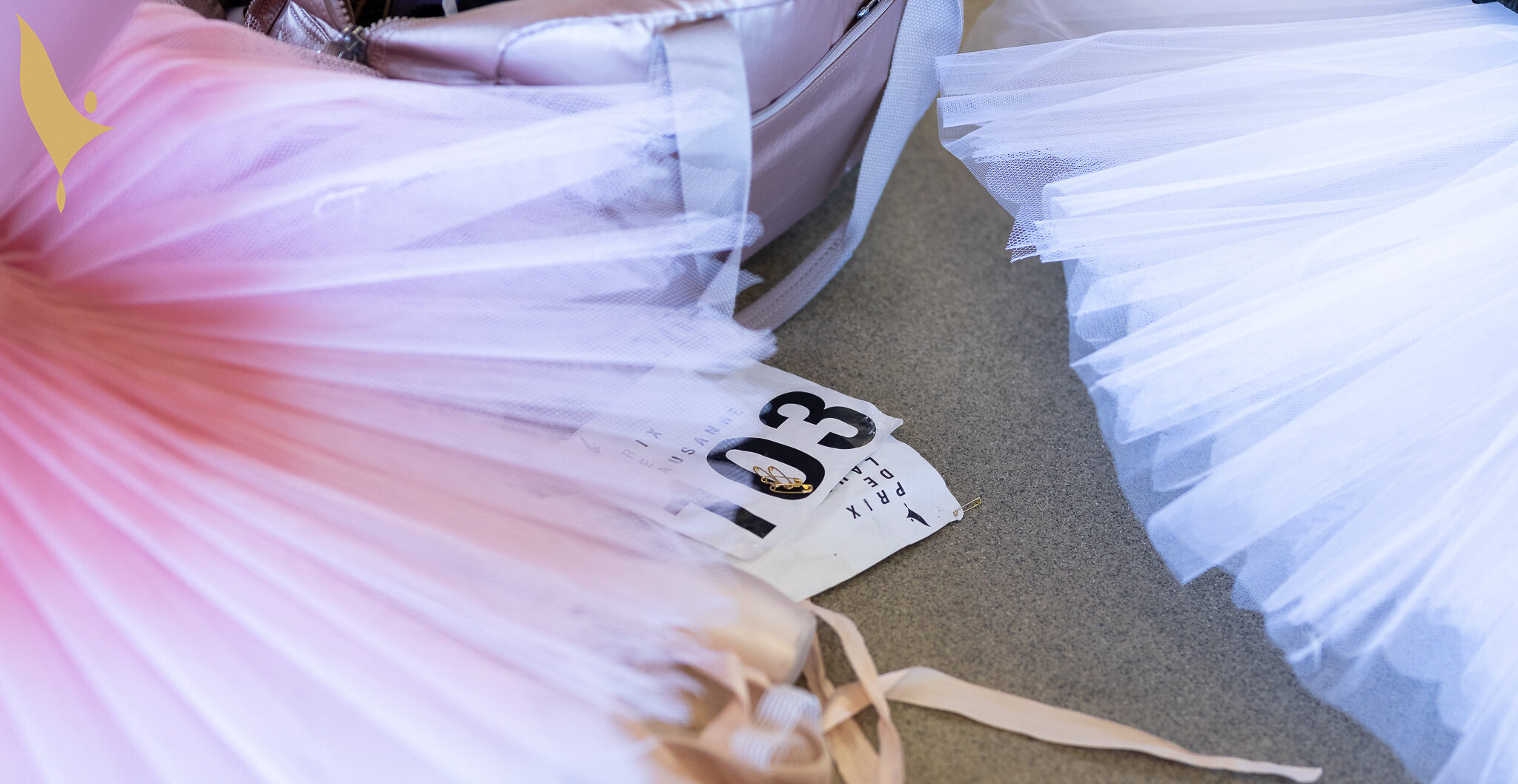 A close-up shot of two Prix competitors' practice tutus, with pointe shoes and audition numbers beneath.