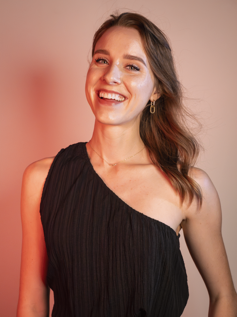 Kirsten Kemp's headshot. She smiles wearing a dark one-shoulder top.