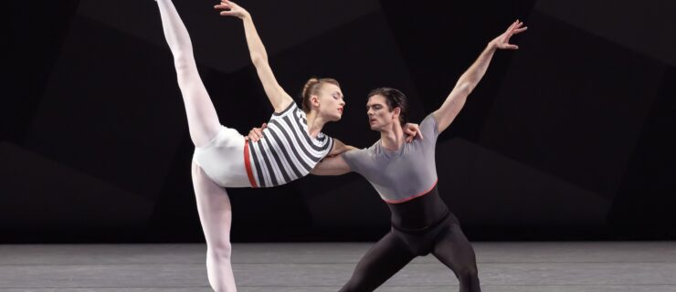 Miriam Miller and Peter Walker dance a pas de deux onstage. Miller, wearing a black and white striped leotard with a red waistband and and white tights, does a penché on pointe facing stage left as Walker lunges next to her, holding her waist. Miller put her arm around Walker's shoulder and lefts her right arm up. Walker wears a gray and black unitard.